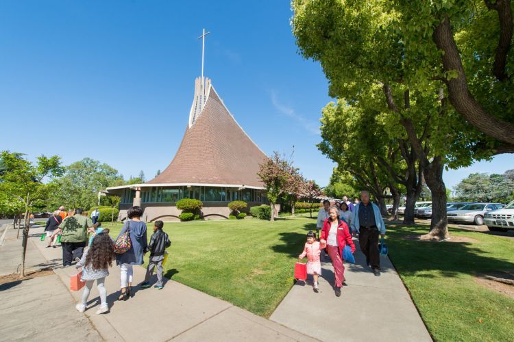 people walk on sidewalk in front of methodist church